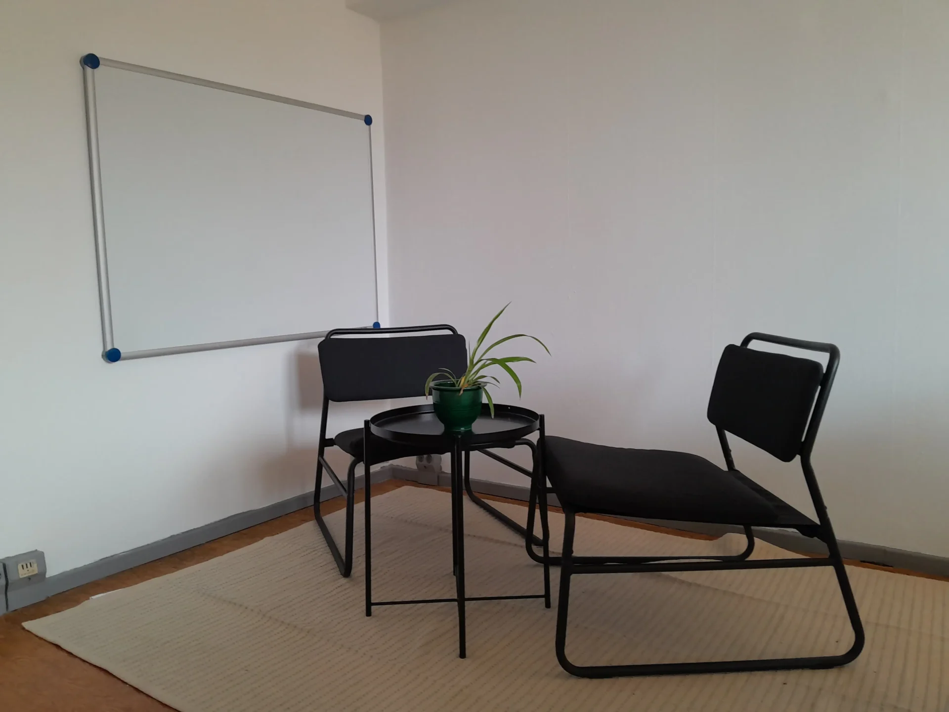 Gruppenraum mit zwei Stühlen, Tisch und einer Magnetwand ist zu sehen.