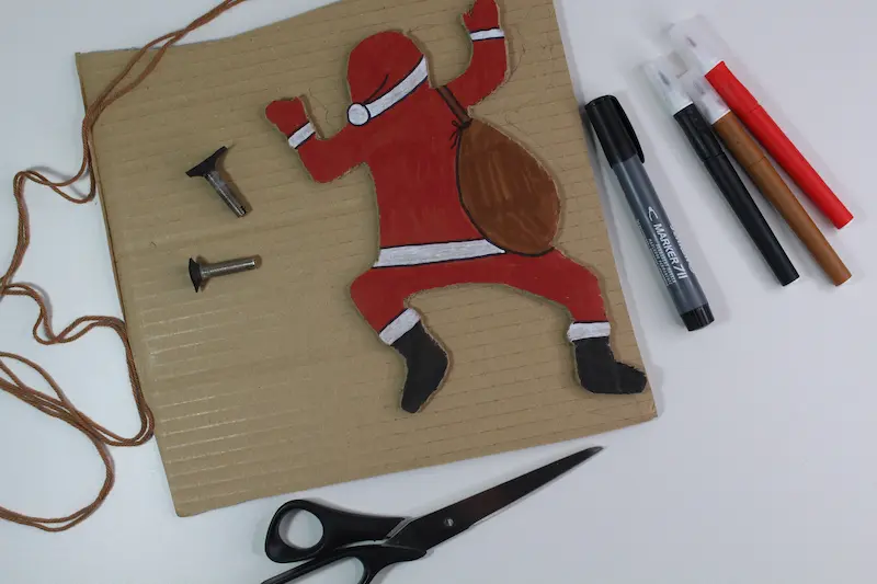 Auf einem Tisch liegen Stifte, Scheren, Bastelwergzeug. Aus Weihnachtsmann aus Pappe wurde gebastelt.
