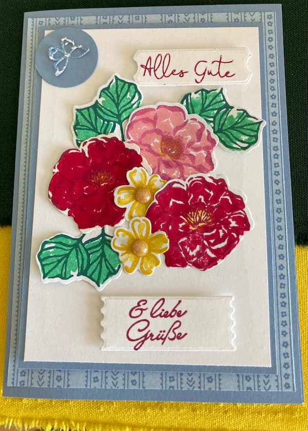 Eine Karte aus Papier mit Blumendekoration und der Aufschrift "Alles Gute und Liebe Grüße!