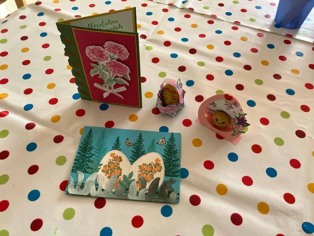 Zu sehen sind zwei Klappkarten aus Papier mit Motiven, die zu Ostern und Frühling passen. Außerdem zwei Körbe aus Papier.