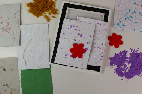 Auf einem Tisch liegen selbst gemachtes Papier in verschiedenen Farben.