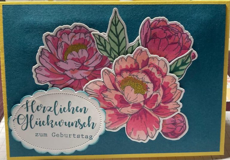 Eine Karte mit blauem Hintegrrund und drei großen, roten Blüten aus Papier. Die Aufschrift lautet " Herzlichen Gkückwunsch zum Geburtstag"